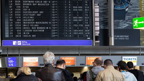 Flughafen-Passagiere vor der Anzeige mit Flügen in Frankfurt