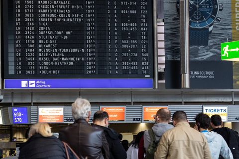 Flughafen-Passagiere vor der Anzeige mit Flügen in Frankfurt