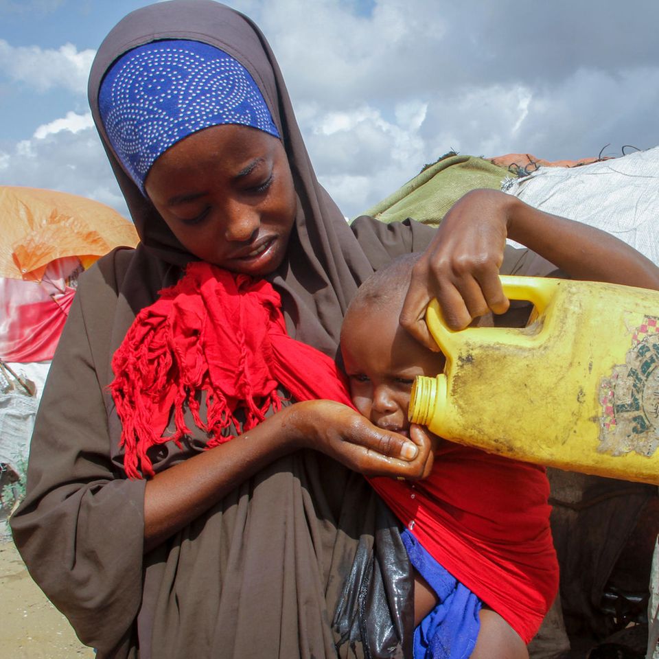 Eine Frau gibt ihrem Kind in einem Flüchtlingslager am Rand der somalischen Hauptstadt Mogadischu Wasser. Dürren und Preisexplosionen bedrohen das Leben von mehreren Millionen Menschen am Horn von Afrika