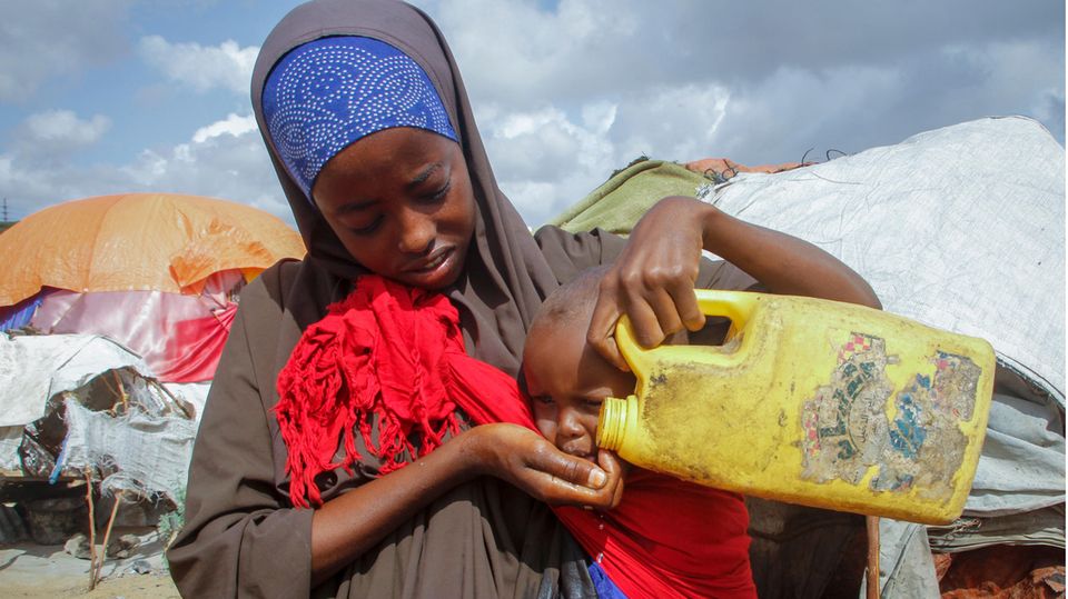 Eine Frau gibt ihrem Kind in einem Flüchtlingslager am Rand der somalischen Hauptstadt Mogadischu Wasser. Dürren und Preisexplosionen bedrohen das Leben von mehreren Millionen Menschen am Horn von Afrika