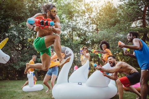 Wasserpistole für Erwachsene: Junge Menschen beschießen sich in einem Park mit Wasserpistolen