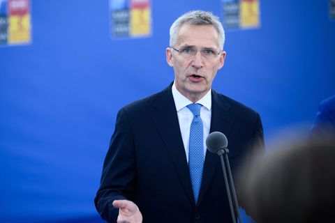 Jens Stoltenberg steht vor einer blauen Wand