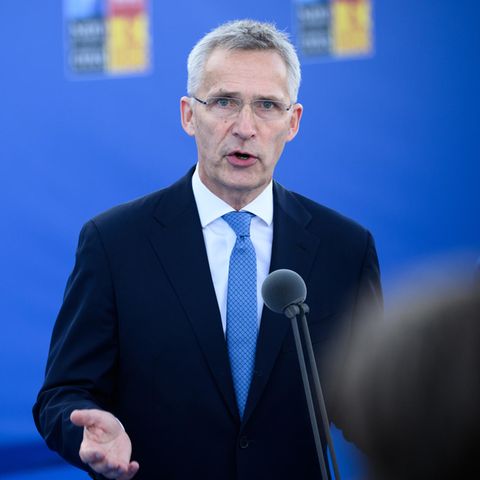 Jens Stoltenberg steht vor einer blauen Wand