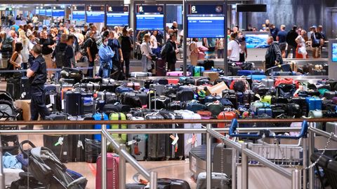 Urlauber am Flughafen Hamburg warten vor einer großen Menge Gepäckstücke