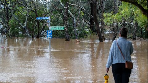 Frau watet durch eine überflutetes Gebiet in Australien