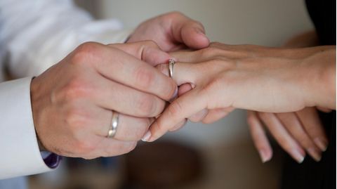 Ein Mann zieht einer Frau einen Verlobungsring über den Finger