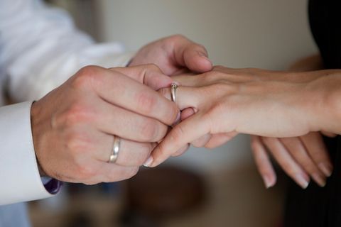 Ein Mann zieht einer Frau einen Verlobungsring über den Finger