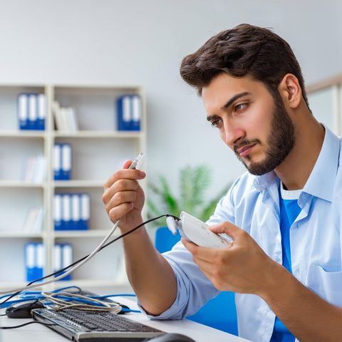 Ein junger Mann hält einen Router und ein Kabel in der Hand