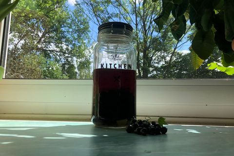 Raffiniertes Rezept: Ansatz mit Johannisbeeren und Doppelkorn steht in einem Einmachglas auf der Fensterbank