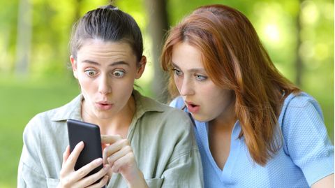 Zwei Frauen schauen geschockt auf ein Smartphone