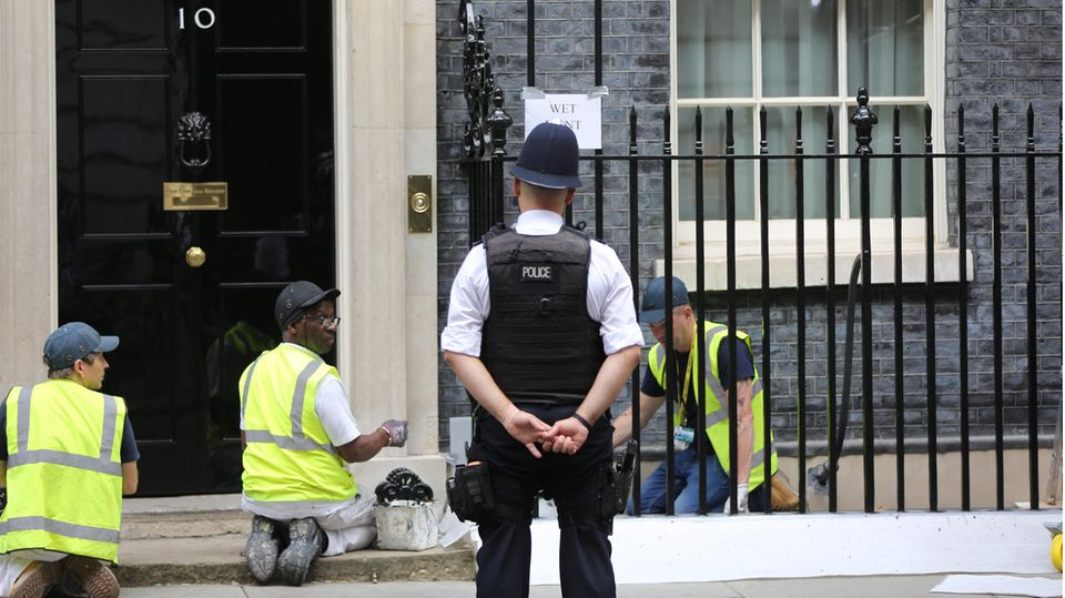 Workers are painting the fence in front of 10 Downing Street, the official residence of the British Prime Minister