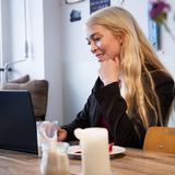 Eine Frau sitzt mit ihrem Laptop in einem Café