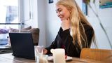 Eine Frau sitzt mit ihrem Laptop in einem Café