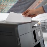 Eine Person legt ein Blatt Papier in einen Kopierer