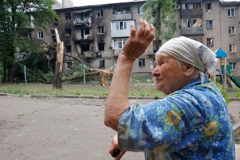Eine Frau geht in der Nähe eines Wohnhauses vorbei, das während des Beschusses von Donezk beschädigt wurde
