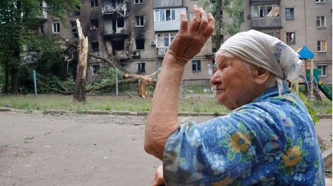 Eine Frau geht in der Nähe eines Wohnhauses vorbei, das während des Beschusses von Donezk beschädigt wurde