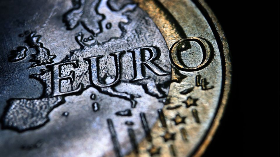 Eine Euromünze mit geprägtem Umriss des europäischen Kontinents und geriffeltem Rand liegt auf schwarzem Untergrund