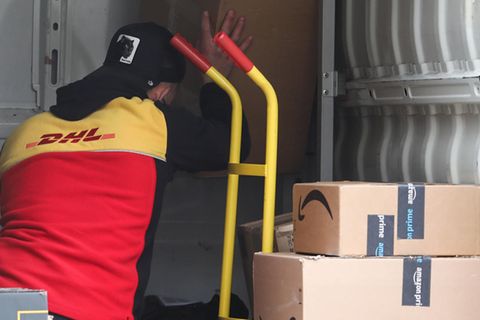 Ein DHL-Paketbote räumt Sendungen aus seinem Wagen