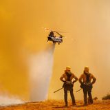 Zwei Einsatzkräfte beobachten einen Chinook-Hubschrauber, der Löschwasser über das "Electra Fire" bei Pine Acres, US-Bundesstaat Kalifornien, abwirft. Das schnell um sich greifende Feuer bedroht mehr als 1200 Gebäude.