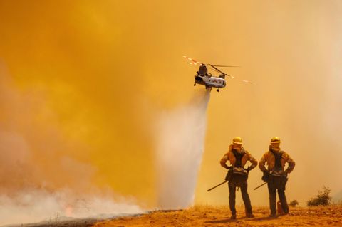 Zwei Einsatzkräfte beobachten einen Chinook-Hubschrauber, der Löschwasser über das "Electra Fire" bei Pine Acres, US-Bundesstaat Kalifornien, abwirft. Das schnell um sich greifende Feuer bedroht mehr als 1200 Gebäude.