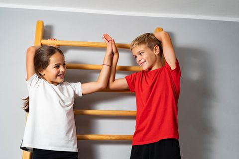 Sprossenwand im Kinderzimmer: Zwei Schulkinder stehen an einer Sprossenwand