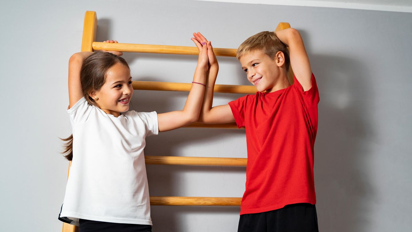 Sprossenwand im Kinderzimmer: Zwei Schulkinder stehen an einer Sprossenwand
