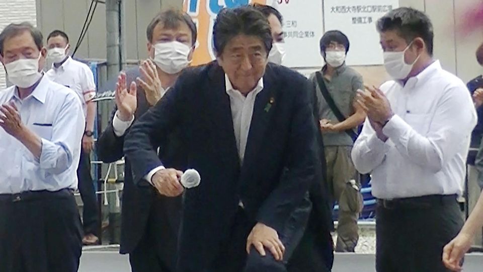 Shinzo Abe betritt die Rednerbühne, dahinter steht der Attentäter