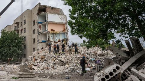 Rettungskräfte stehen auf den Trümmern eines Wohnblocks nach einem Raketeneinschlag in der Region Donezk in der Ostukraine