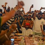 Demonstranten haben sich um einen Konferenztisch versammelt, jubeln und machen Fotos und Videos