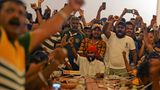 Demonstranten haben sich um einen Konferenztisch versammelt, jubeln und machen Fotos und Videos