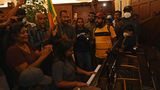 Eine Frau begleitet den Protest musikalisch auf einem Piano, während sie bejubelt wird