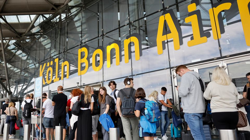 Reisende warten in einer langen Schlange am Flughafen Köln-Bonn