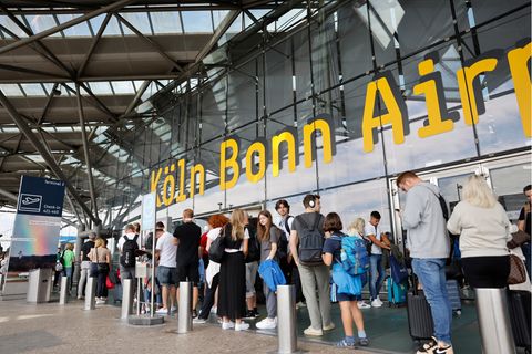 Reisende warten in einer langen Schlange am Flughafen Köln-Bonn