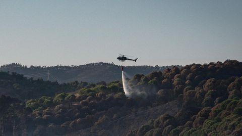 Hubschrauber bei Löscharbeiten über einem brennenden Wald in Portugal