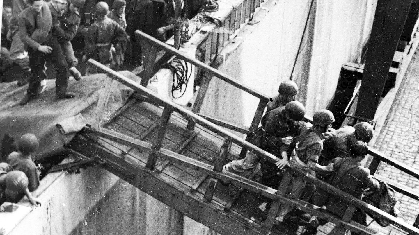 Britische Soldaten tragen einen Geflüchteten zurück auf das Hamburger Dock.