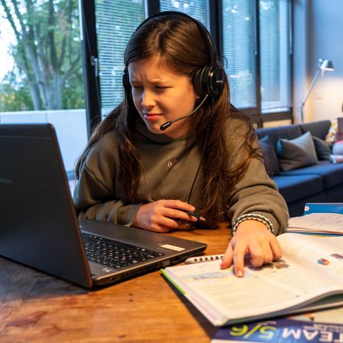 Schule und Corona: Mädchen am Computer mit Schulbüchern