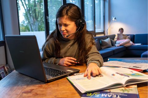 Schule und Corona: Mädchen am Computer mit Schulbüchern