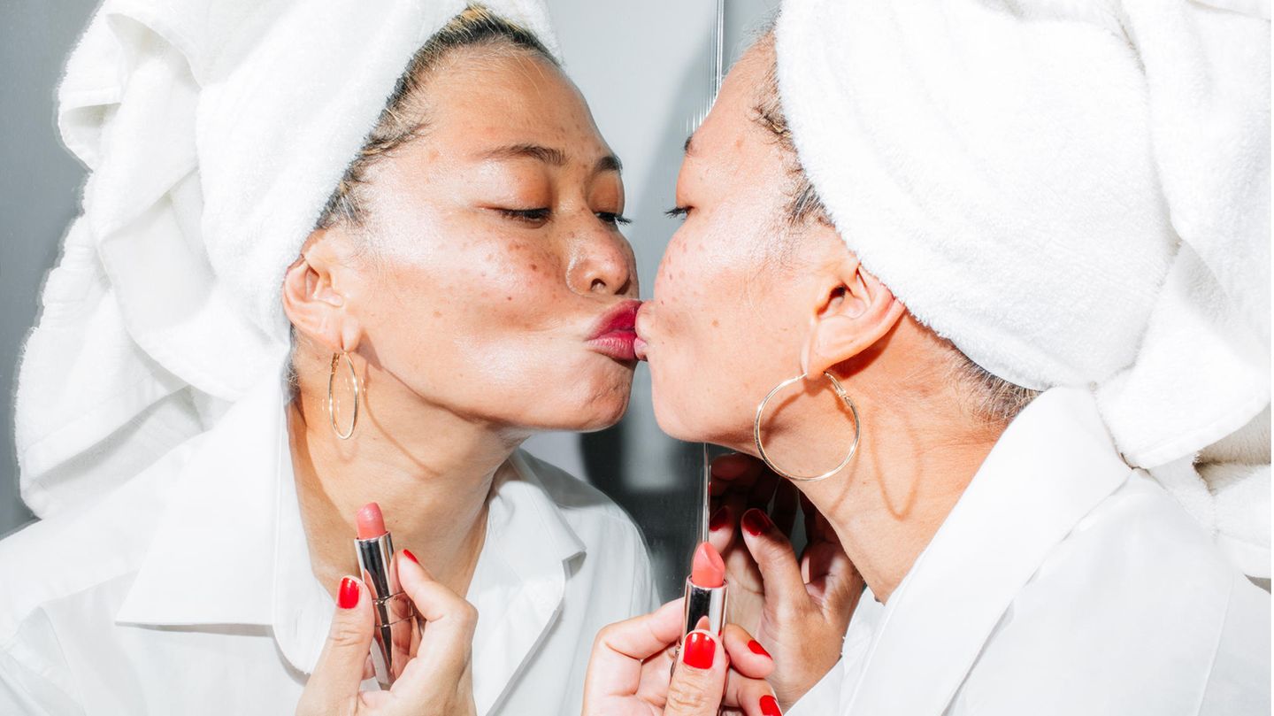 Eine Frau im Bademantel küsst sich selbst im Spiegel