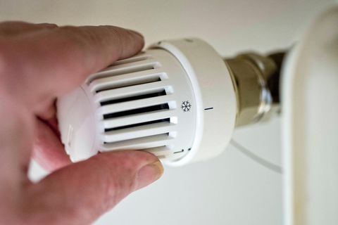 Symbol in der Energiekrise: Eine Hand dreht am Thermostat einer Heizung