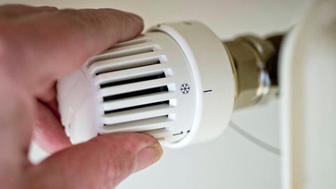 Symbol in der Energiekrise: Eine Hand dreht am Thermostat einer Heizung