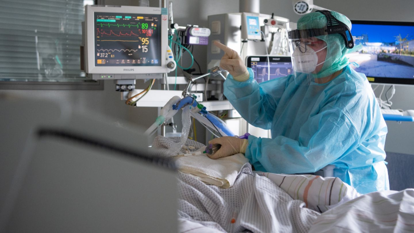 Eine Intensiv-Pflegerin versorgt einen schwer an Corona erkrankten Patienten auf der Intensivstation