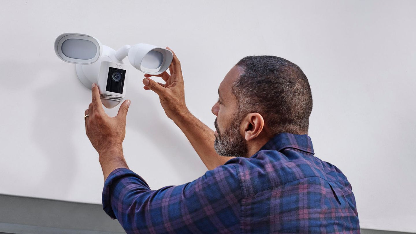 Ein Mann bringt eine Ring-Kamera an einem Haus an