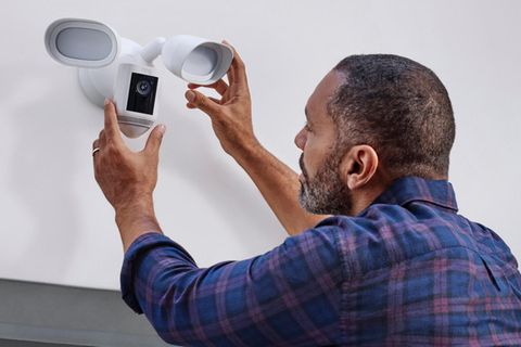 Ein Mann bringt eine Ring-Kamera an einem Haus an