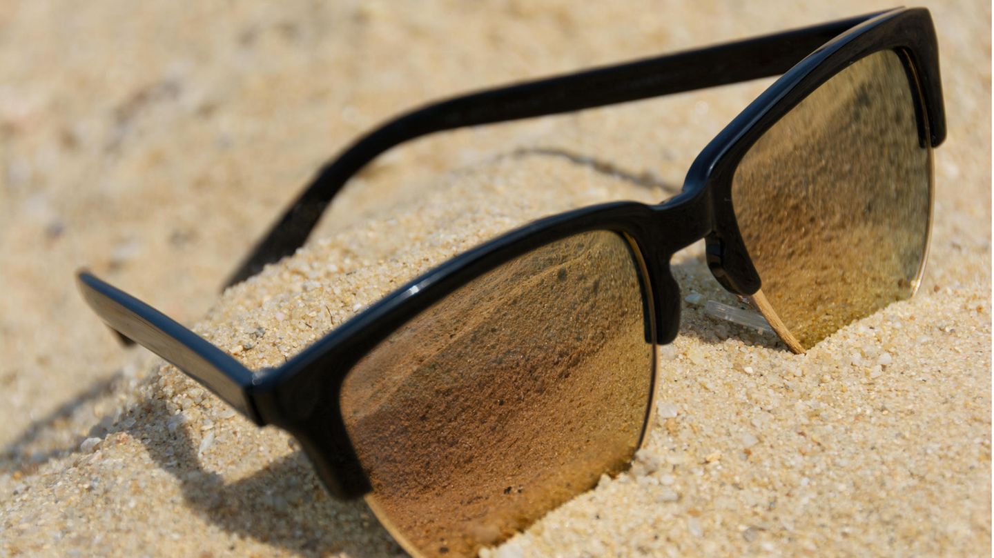 Eine Sonnenbrille liegt im Sand