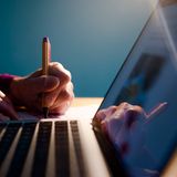 Eine Frau sitzt zu Hause vor ihrem Laptop an einem Schreibtisch