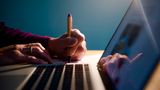 Eine Frau sitzt zu Hause vor ihrem Laptop an einem Schreibtisch