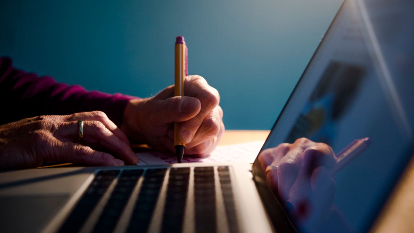 Eine Frau sitzt zu Hause vor ihrem Laptop an einem Schreibtisch