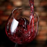 Rotwein wird in ein Glas eingeschenkt