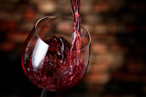 Rotwein wird in ein Glas eingeschenkt
