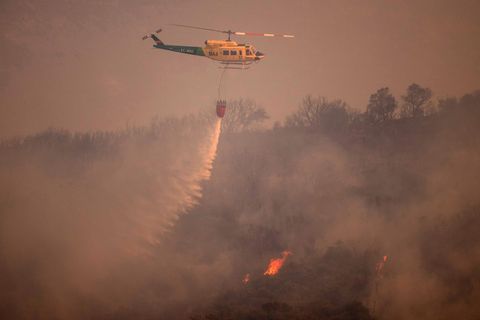 Ein Helikopter wirft Wasser über das Feuer in der Sierra de Mijas